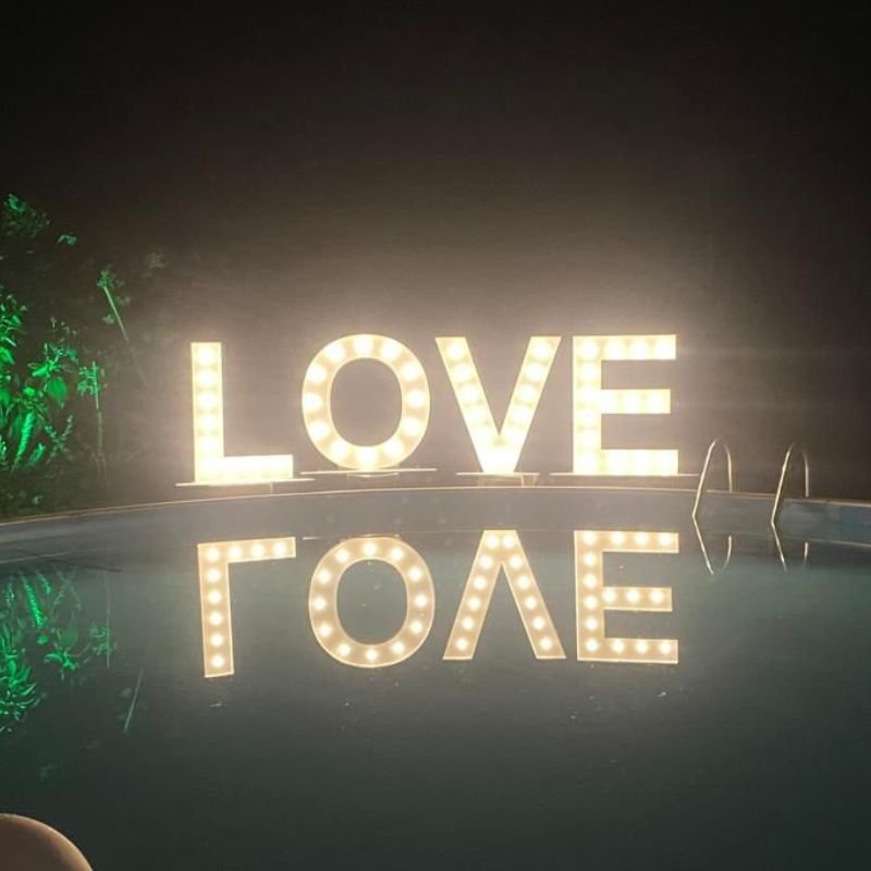 Verlichte LOVE lichtletters bij een zwembad in de avond